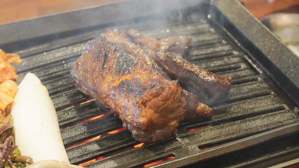 Bracken fern and kimchi grilling alongside the pork jowl