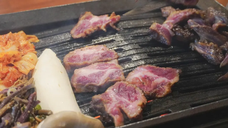 Straw-fired pork jowl cooking on the charcoal grill