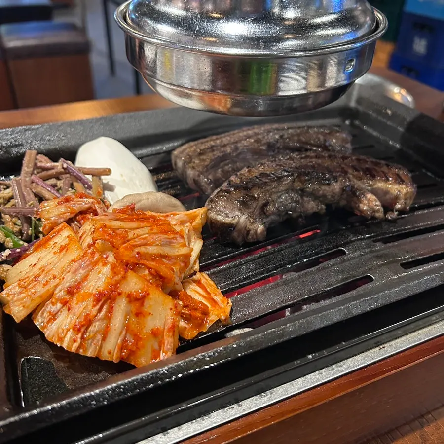Pork belly on the grill with Taebaek kimchi, bracken fern, and king oyster mushrooms