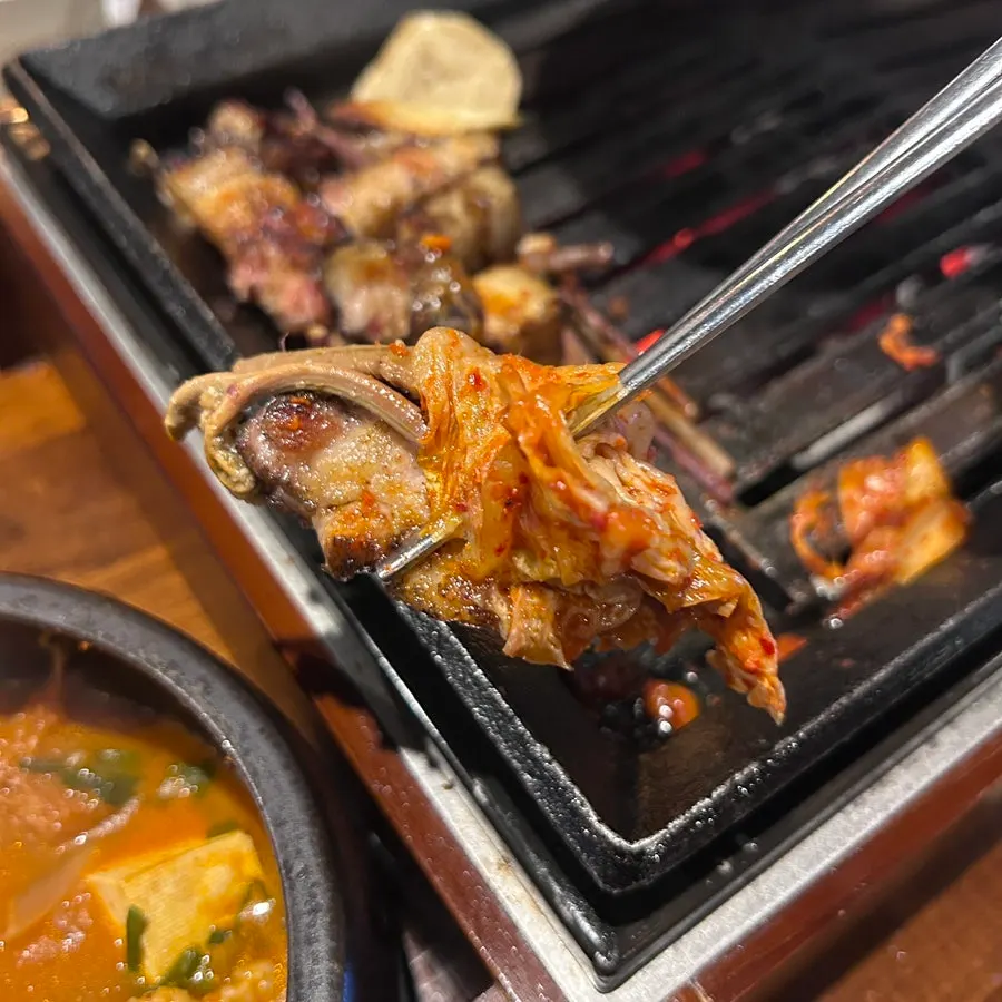 A piece of straw-fired pork belly eaten with Taebaek kimchi