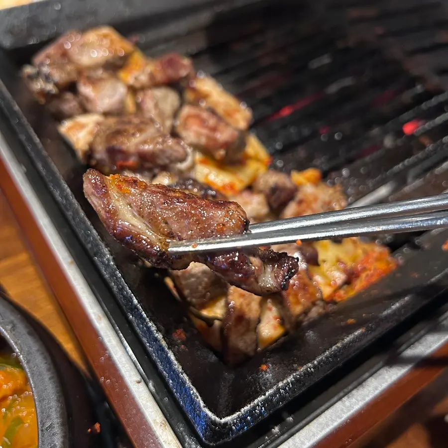 Pork neck being grilled with Taebaek kimchi on the grill