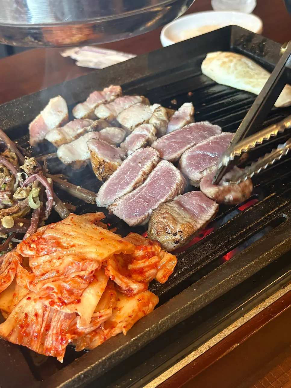Staff member grilling meat with bracken fern and kimchi