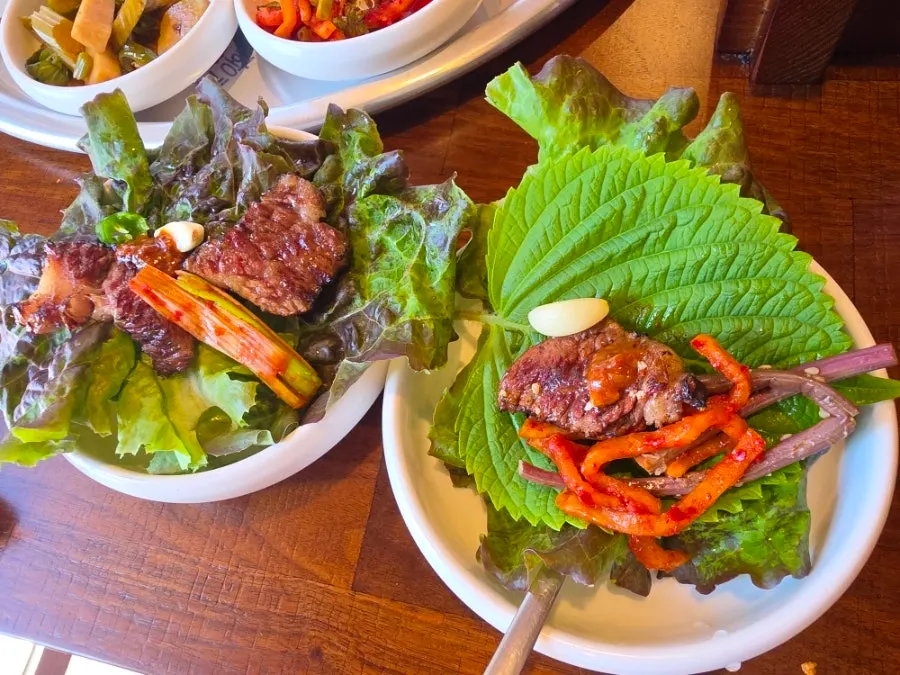 A lettuce wrap piled with meat and side dishes
