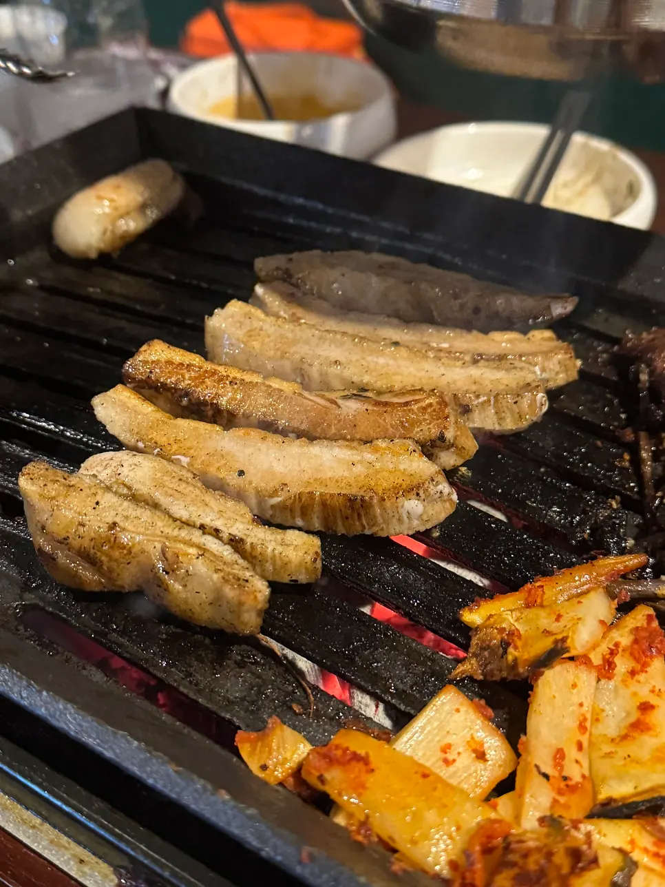 Pork jowl cut into long strips being grilled