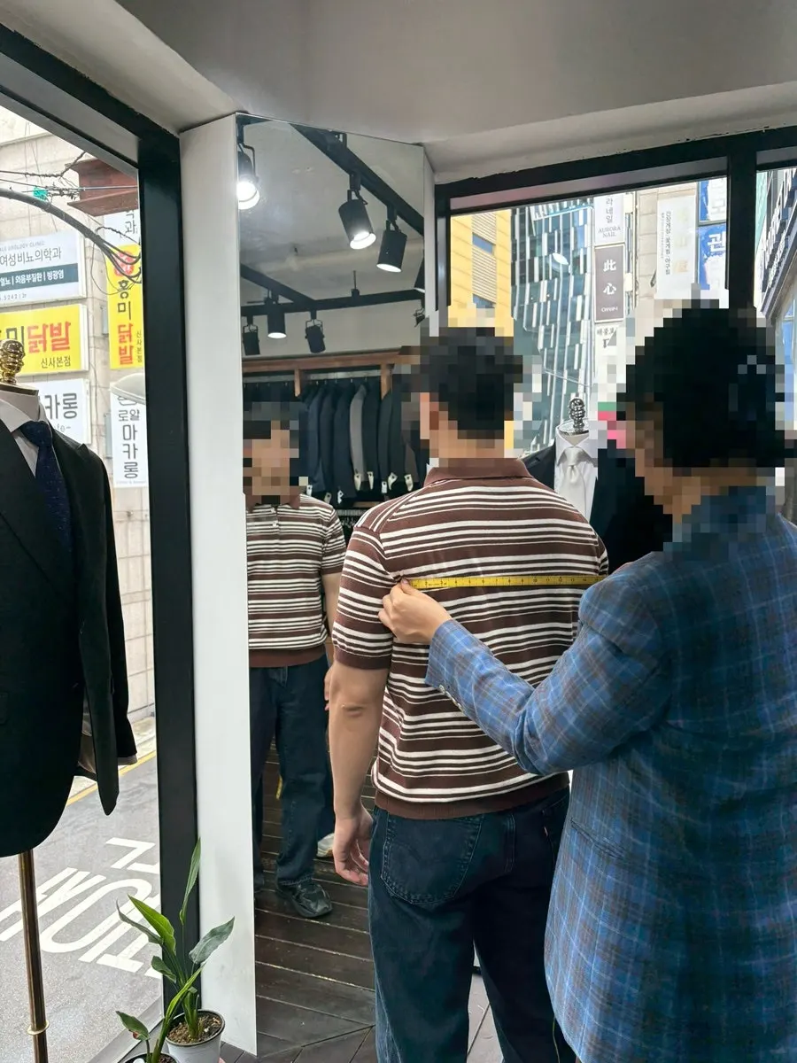 Measuring arm length during a custom suit consultation