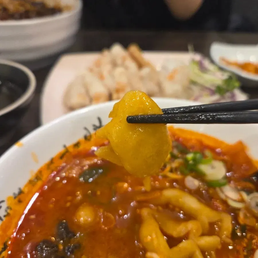 Thick sujebi dumplings lifted out of the bowl