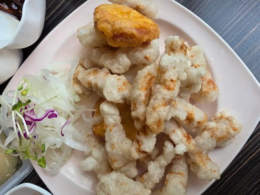 A small plate of sticky rice sweet and sour pork with sauce served on the side