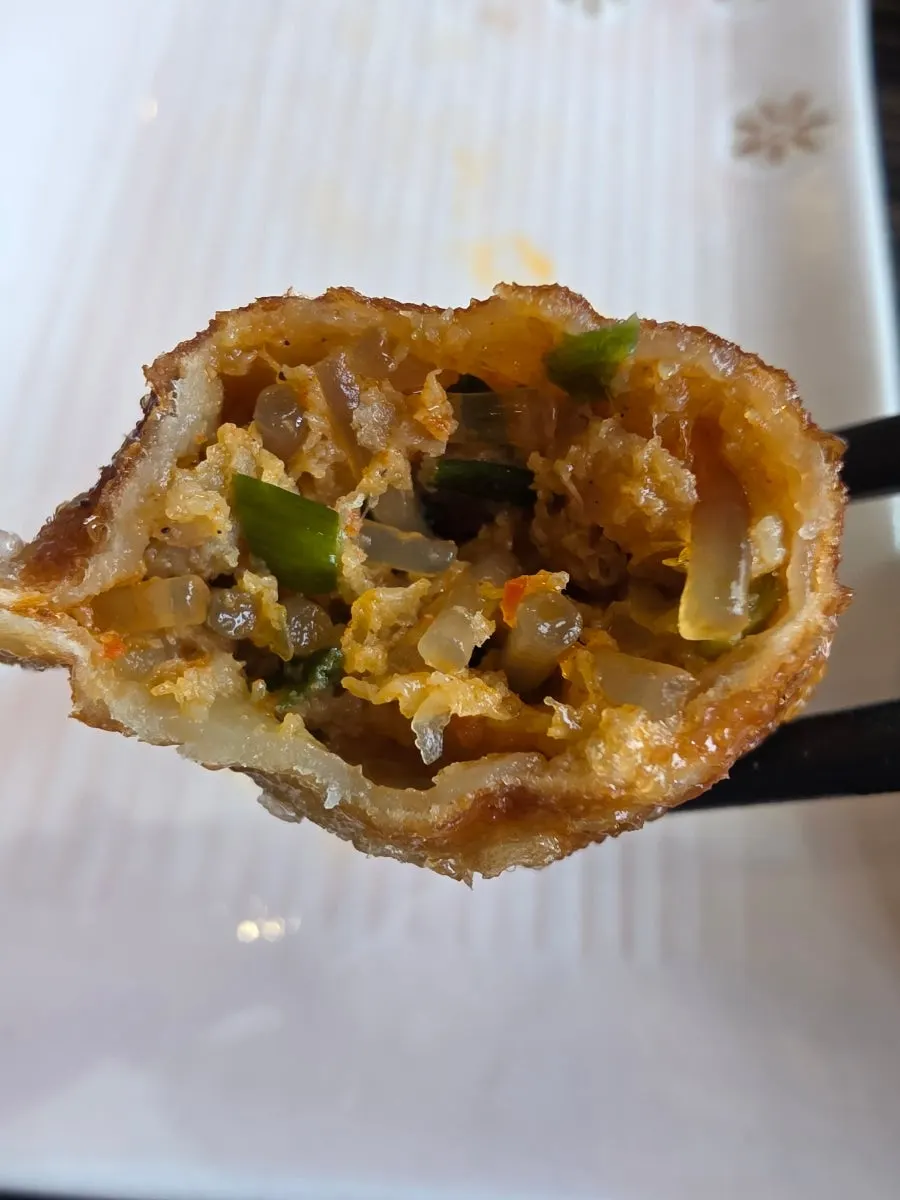 A jjamppong dumpling cut in half showing the filling