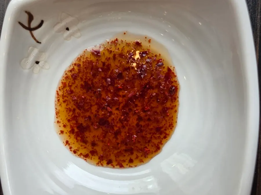 A dish of dumpling dipping sauce with chili flakes added