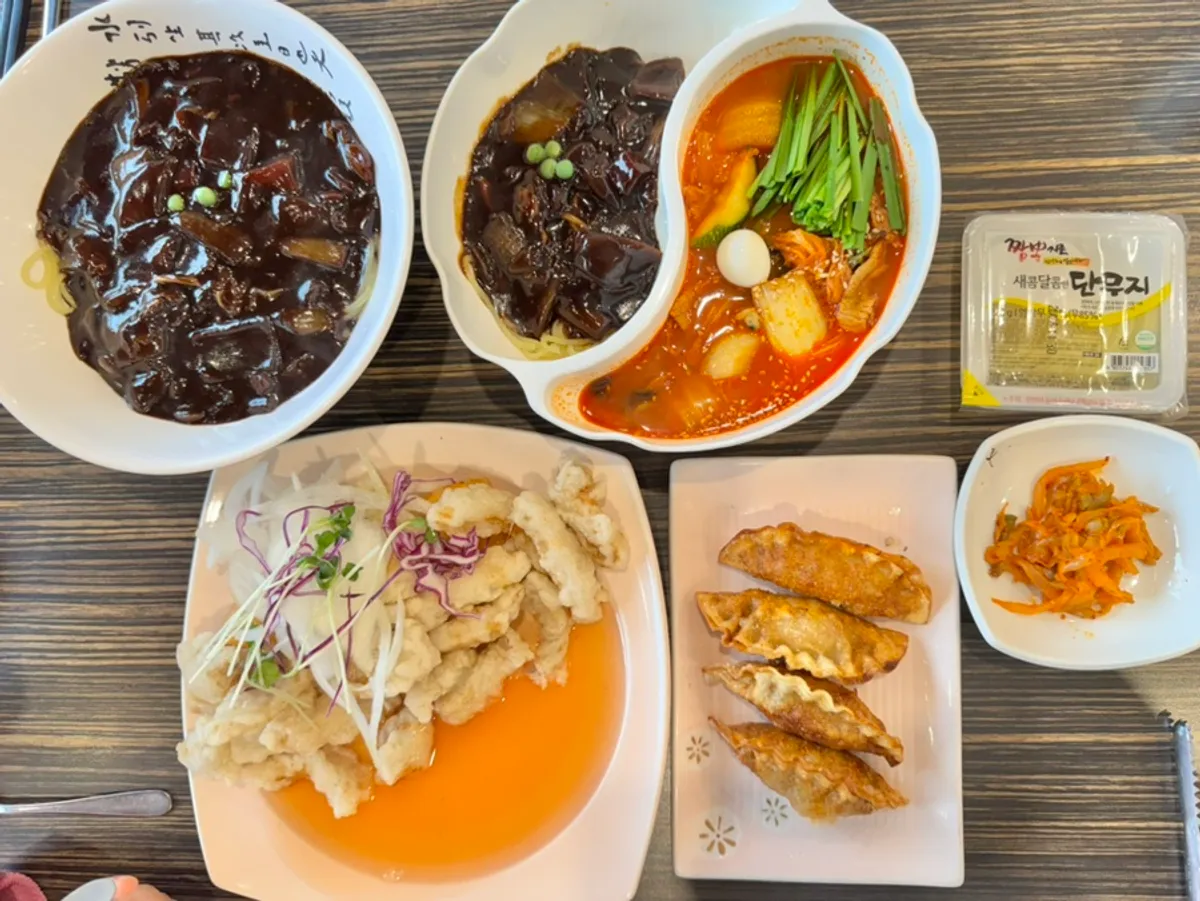 Table spread with jjajangmyeon, jjamjjamyeon, sweet rice tangsuyuk, and jjamppong fried mandu