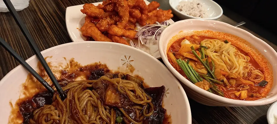 Table with Sichuan sweet and sour pork alongside the noodle dishes