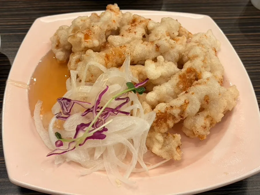 A plate of rice-flour sweet and sour pork with sauce poured over it
