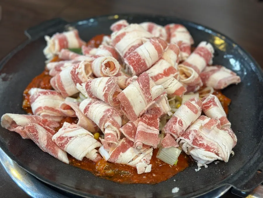 Sizzling pan of octopus starting to cook at the table