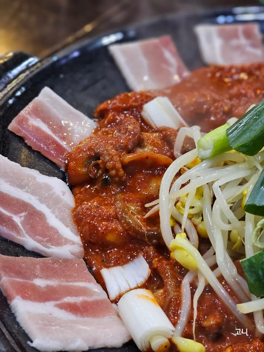 Octopus with pork belly cooking on the hot plate with a smoky char