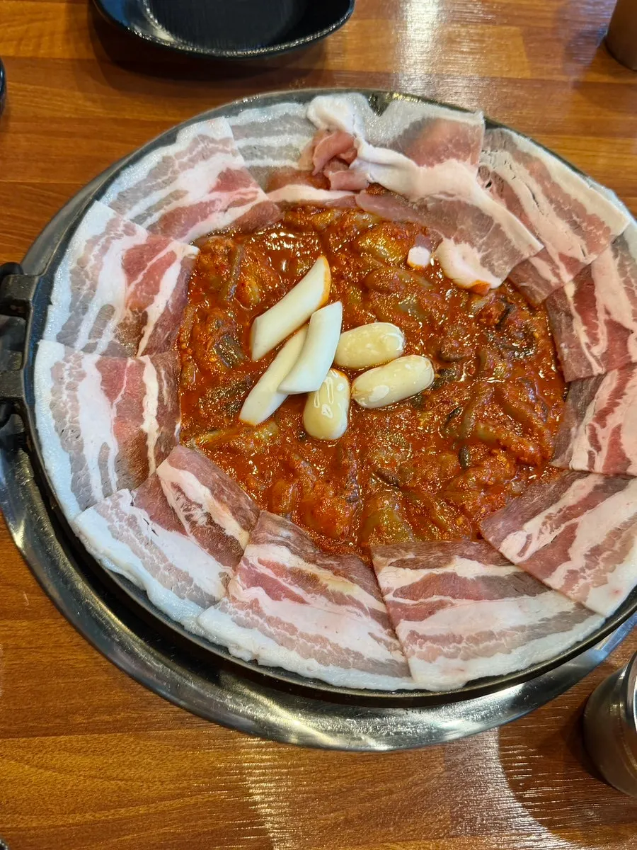 Griddle of jjusamgyeop topped with rice cake and cheese rice cake
