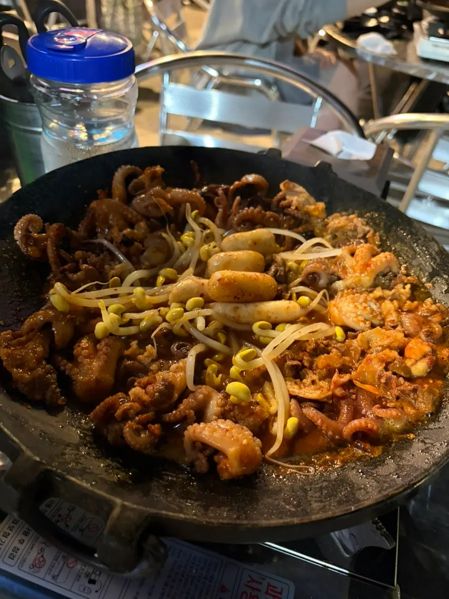 Staff member grilling jjuusam on the hot plate