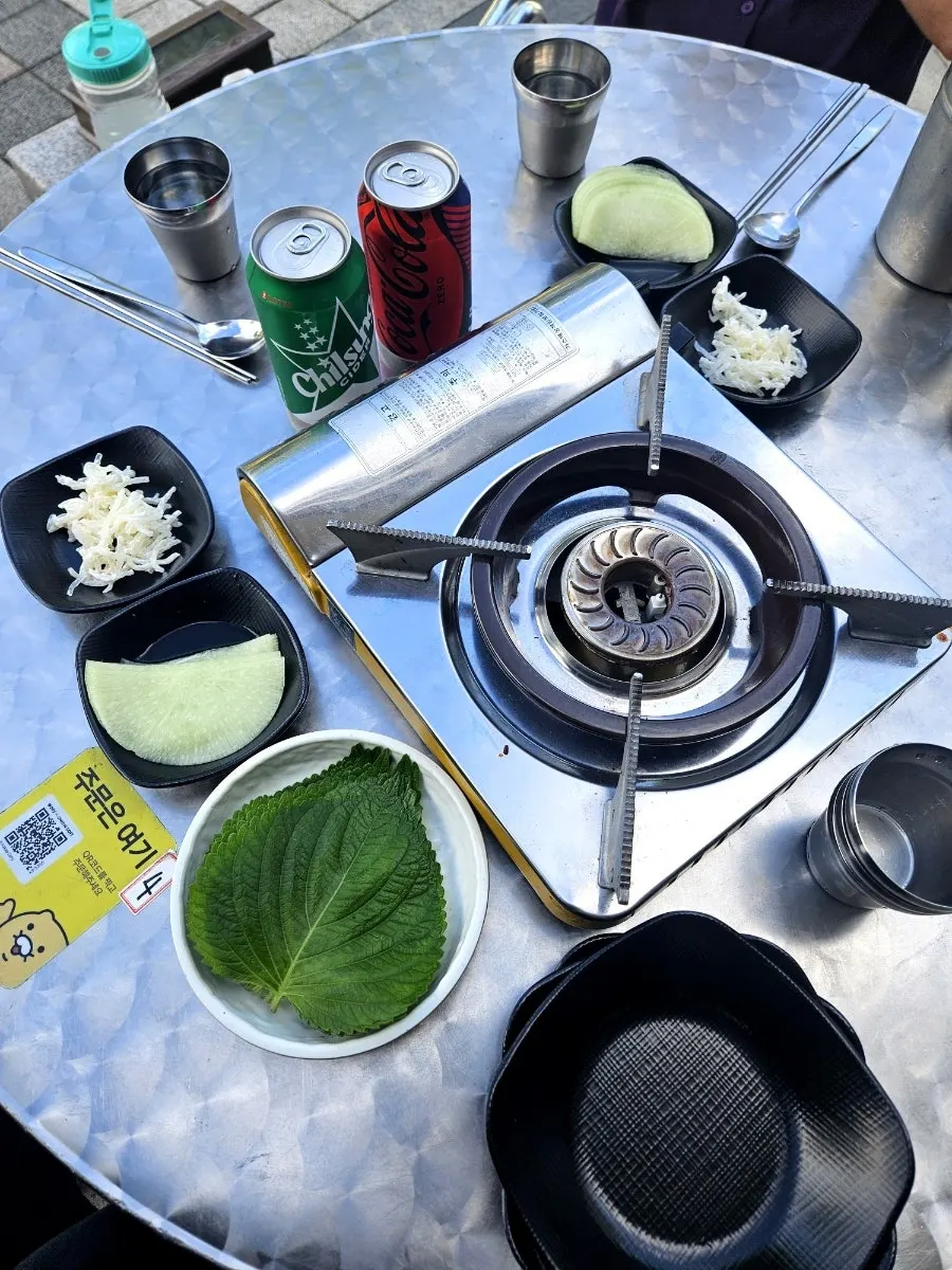 Side dishes including pickled radish, glass noodle salad, and perilla leaves