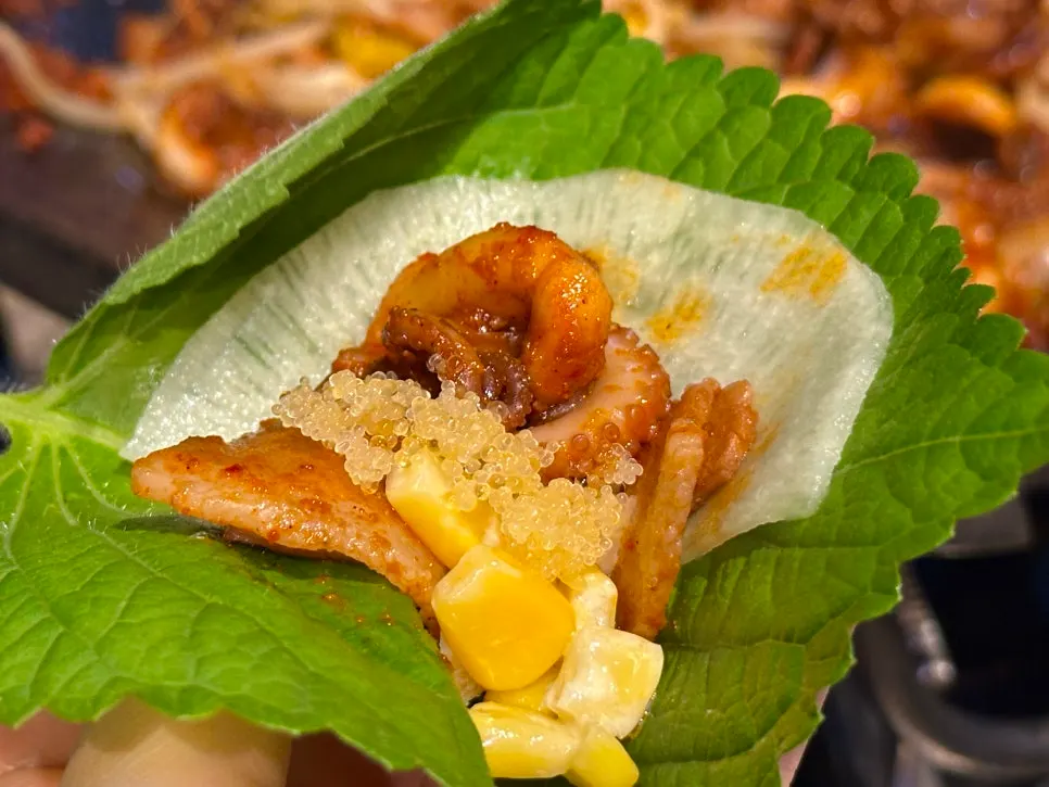 A wrap of perilla leaf and pickled radish topped with octopus and pork belly