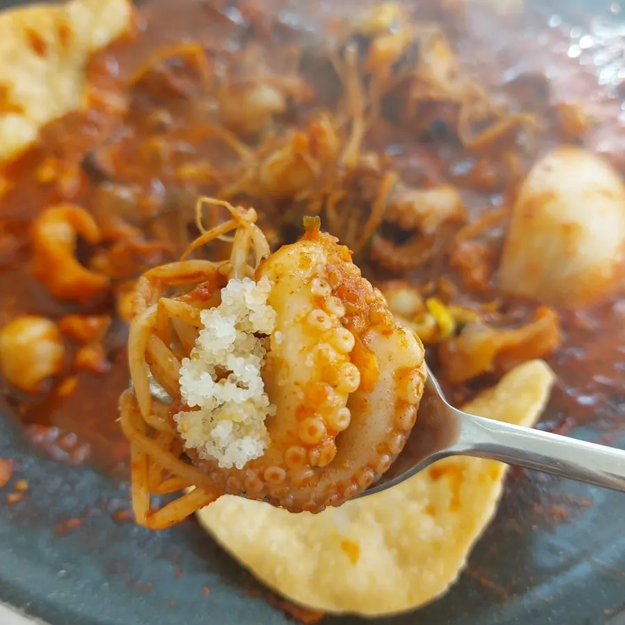 A bite of jjukkumi ssam with mayo sauce