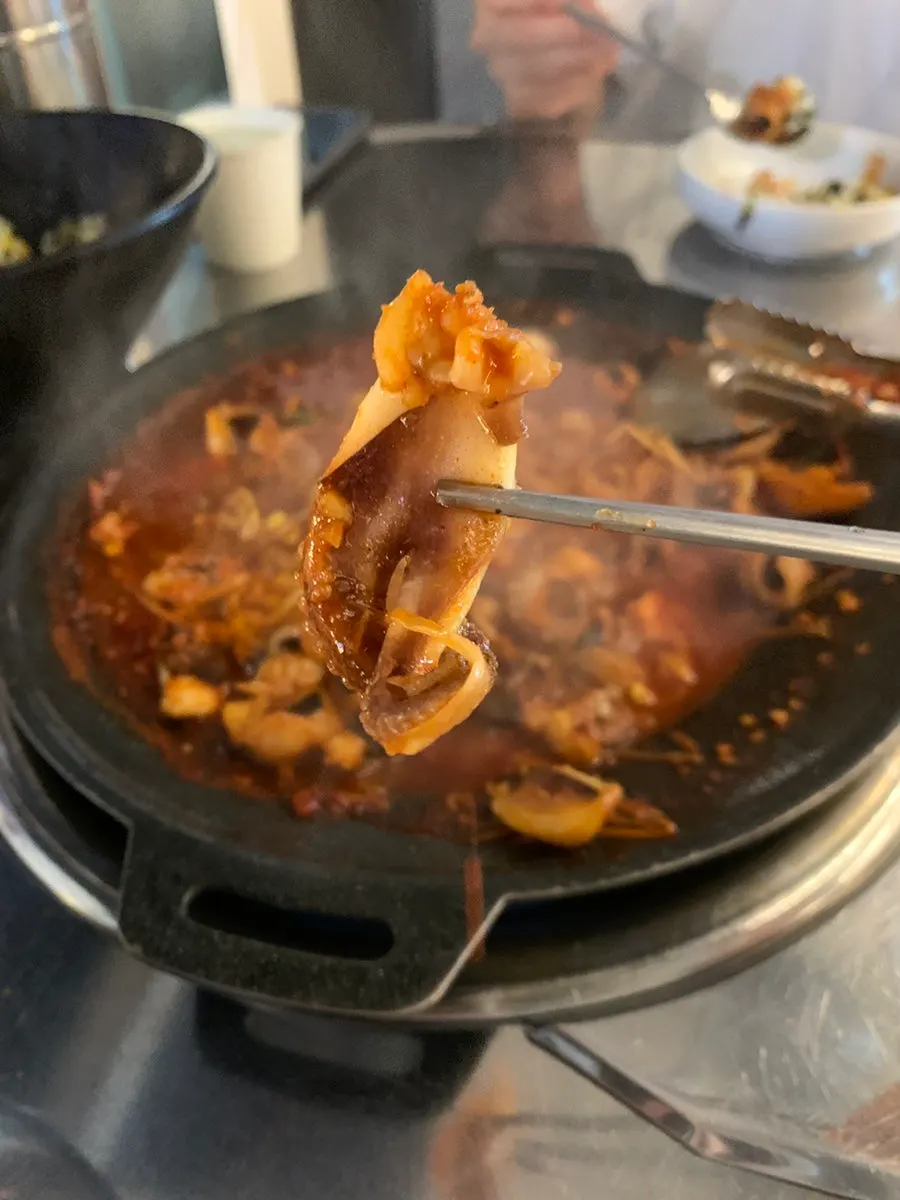 젓가락으로 집어 든 큰 쭈꾸미 한 점