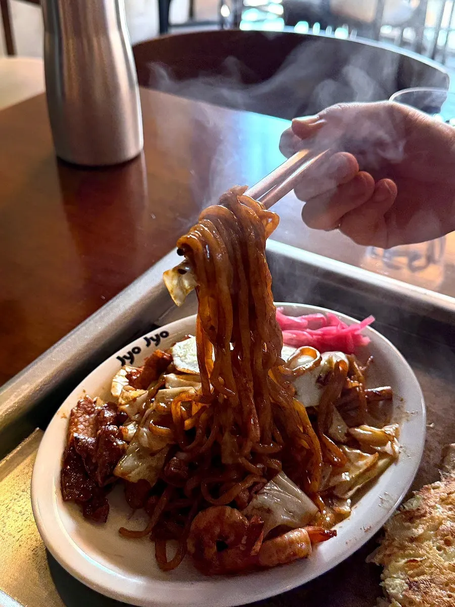 Okonomiyaki being grilled after being flipped