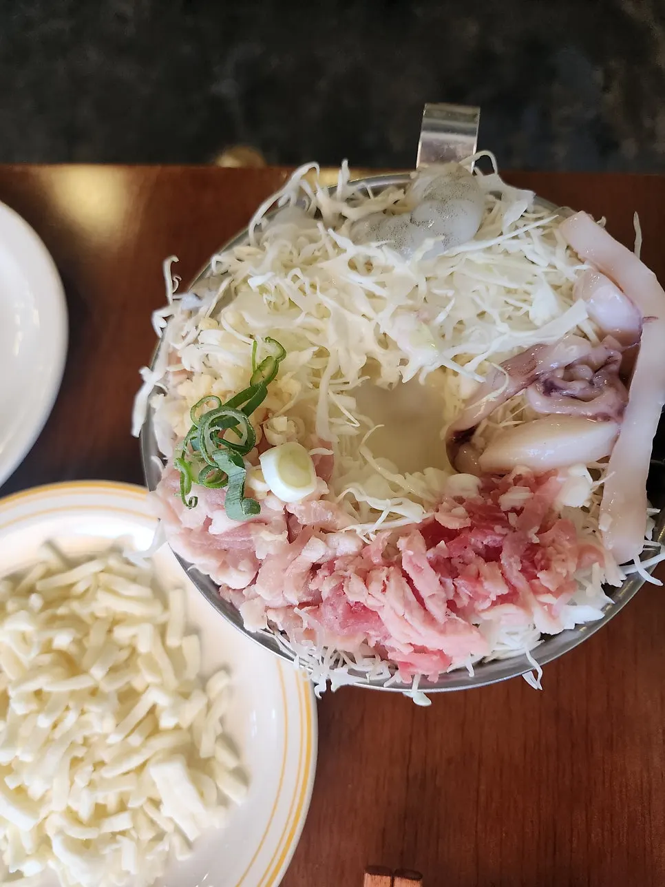 Bowl of okonomiyaki batter with cabbage, shrimp, squid, and pork