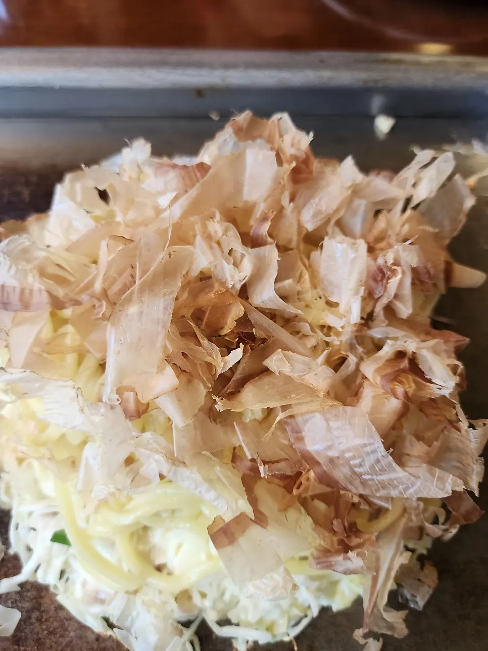 Layering modan-myeon noodles onto the okonomiyaki as it cooks