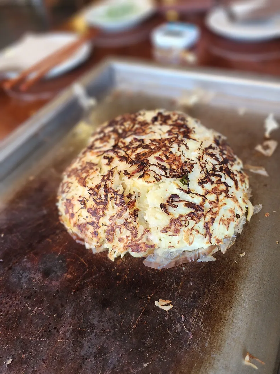 Okonomiyaki on the teppan topped generously with bonito flakes
