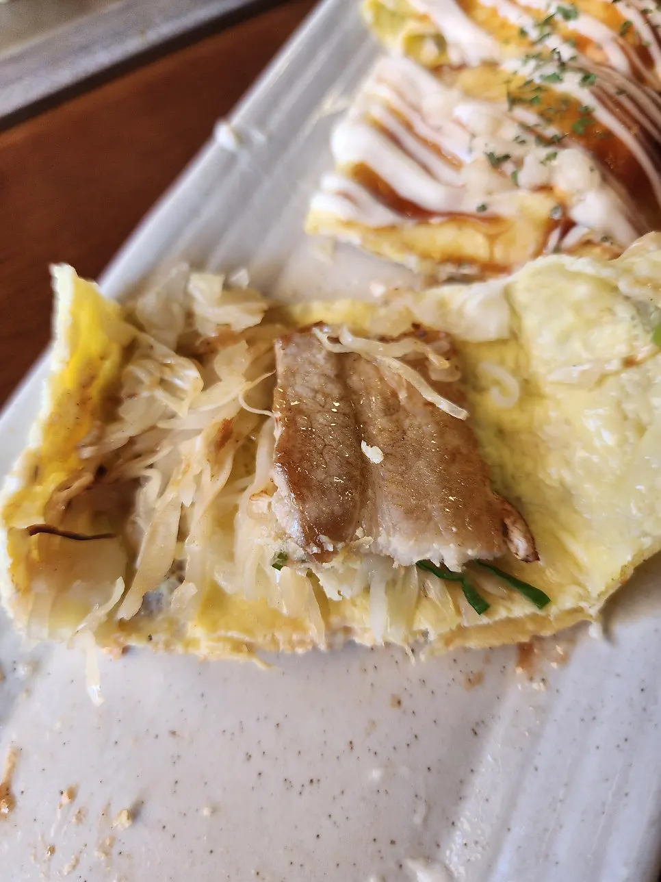 Cross-section of donpeyaki showing pork belly and cabbage inside the egg wrap