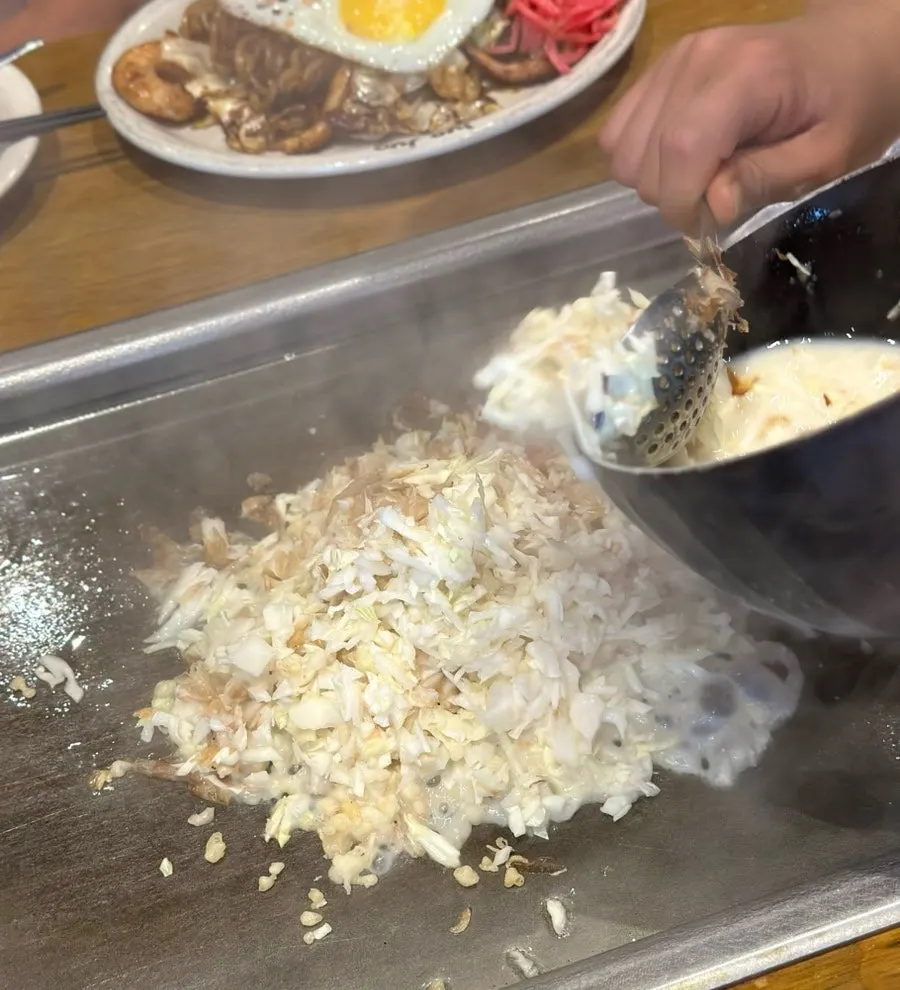 직원이 철판에서 몬자야끼 반죽을 섞는 모습