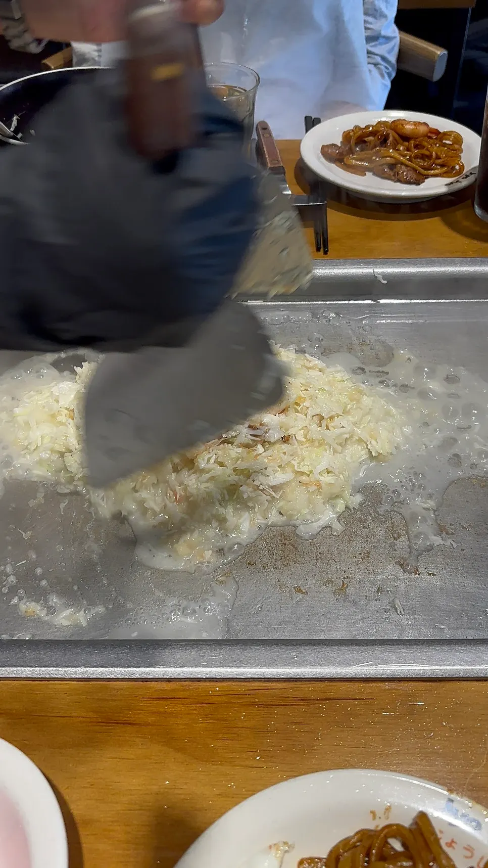 Staff member cooking monjayaki on the teppan