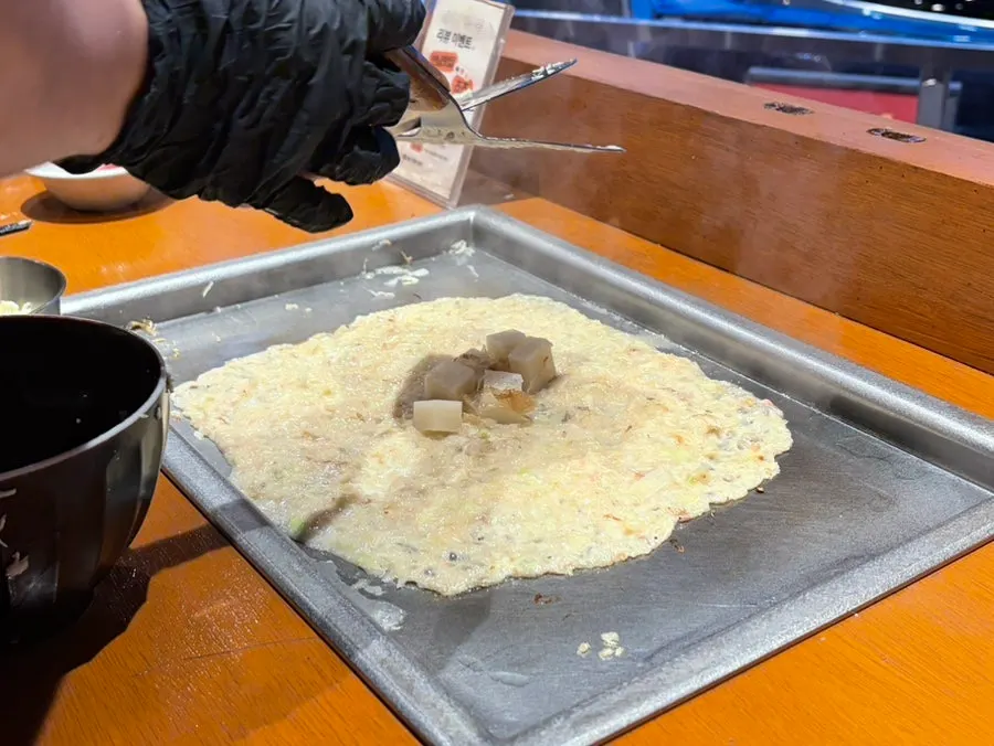 Scooping up the crispy edges of the monjayaki off the griddle