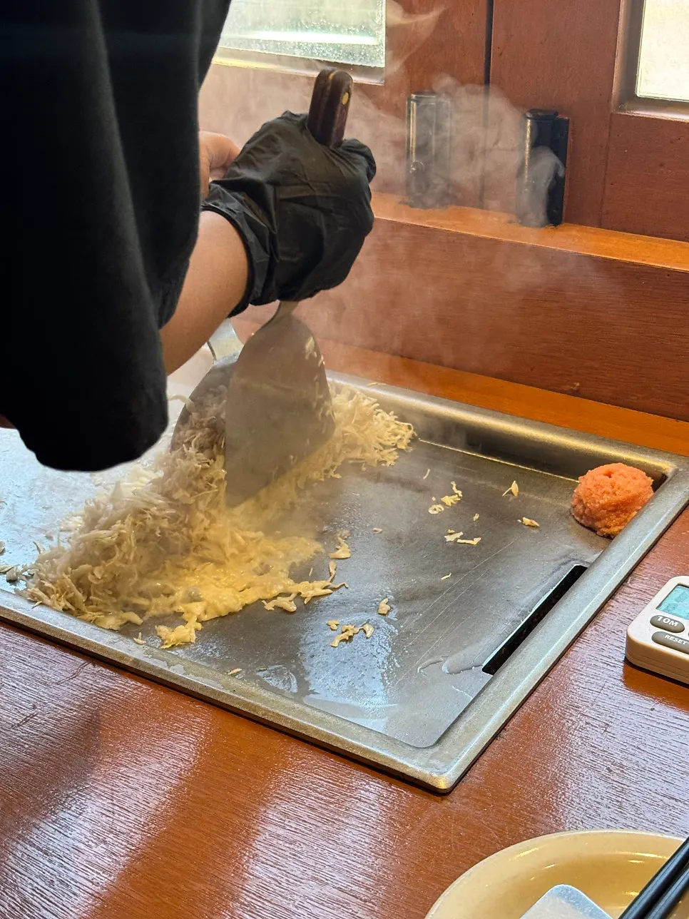 Staff member cooking monjayaki on the griddle