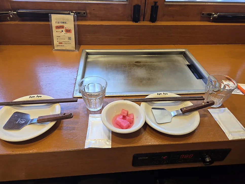 Basic table setup with water cup, chopsticks, mini spatula, and pickled radish