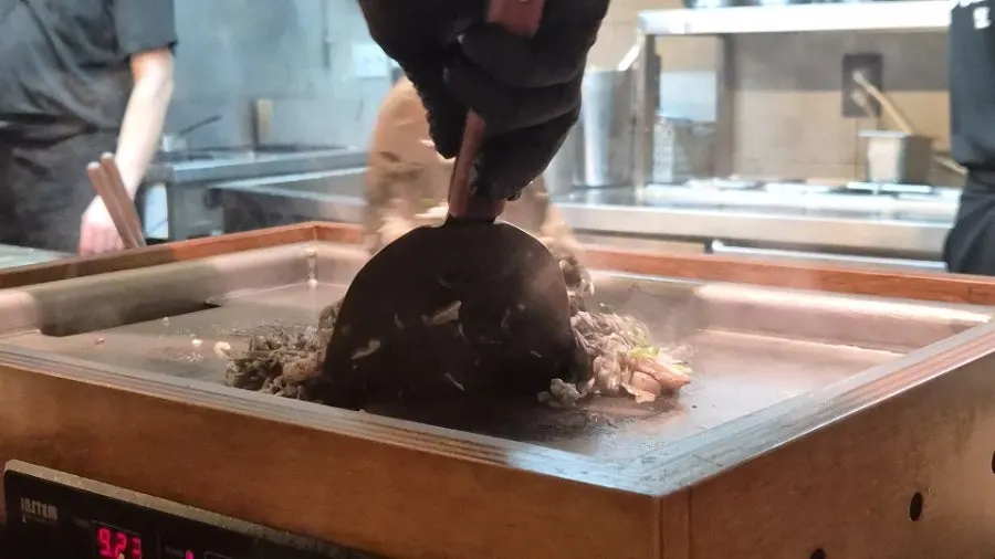 Squid ink monjayaki being stir-fried on the griddle
