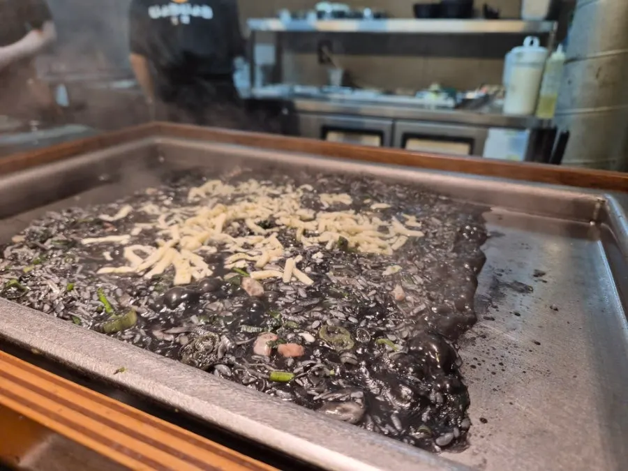Scooping squid ink monjayaki with a small spoon