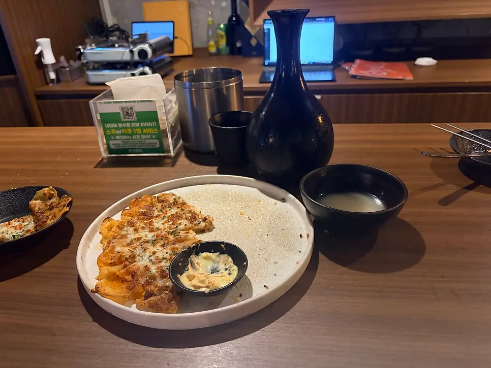 A piece of potato jeon next to a cup of dongdongju