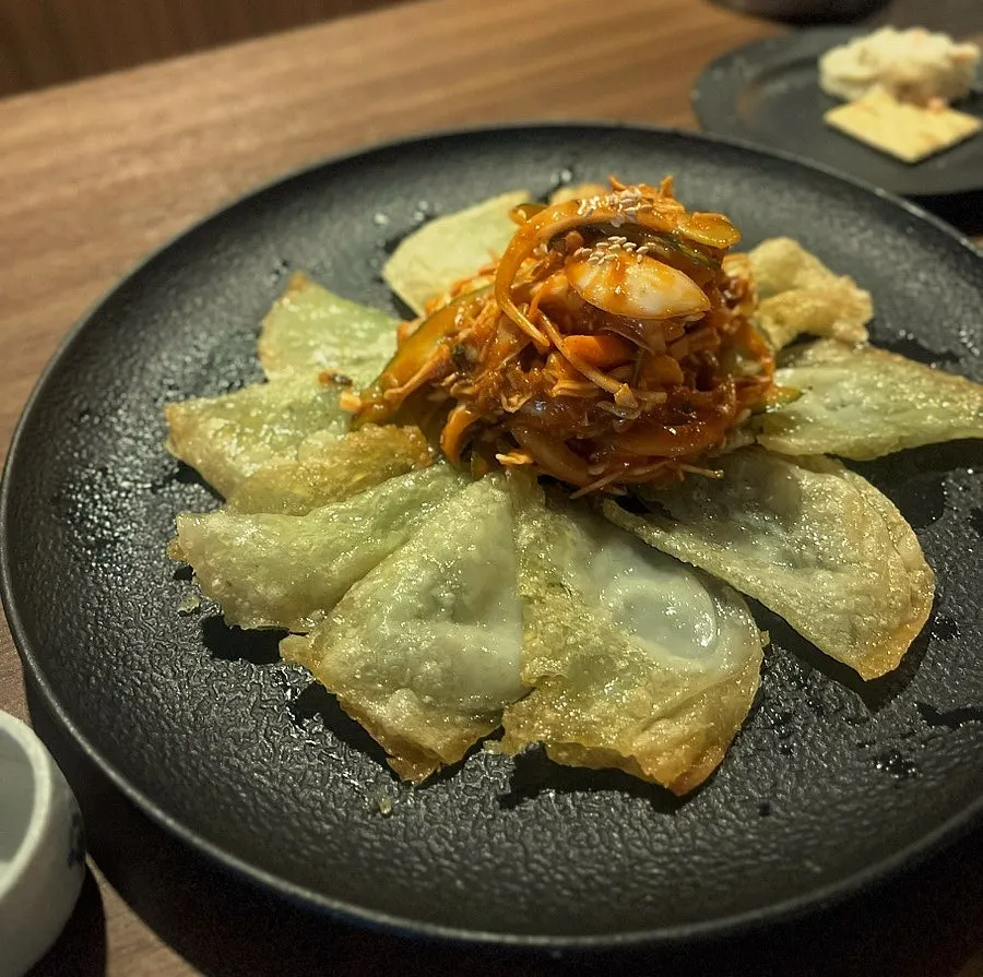 바삭하게 구운 납작만두 위 야채무침 한 접시