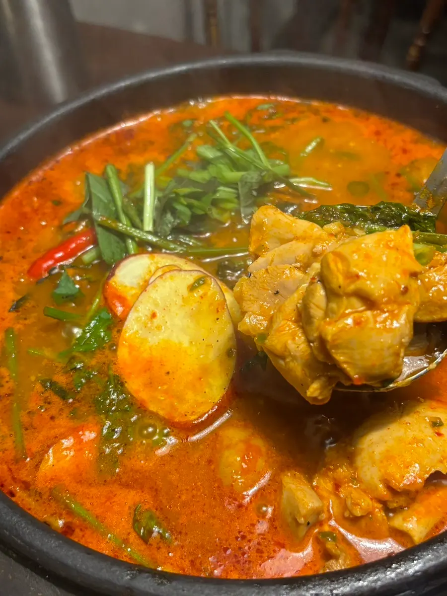 Pot of mul dakgalbi topped with minari and perilla leaves