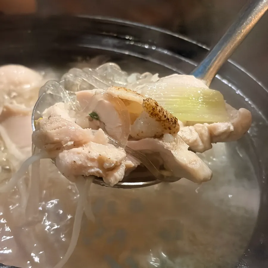 A small bowl of clear broth and chicken meat