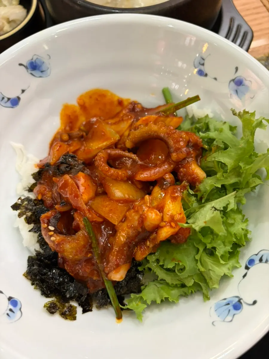 Sesame oil on the table with octopus stir-fry bibimbap being prepared