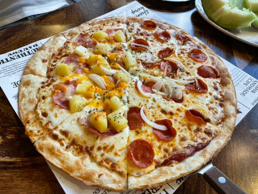 A slice of thin pizza with stretchy melted cheese