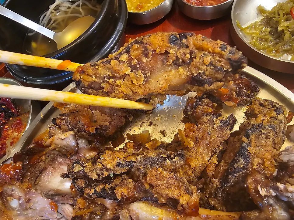 A piece of fried jokbal held with chopsticks