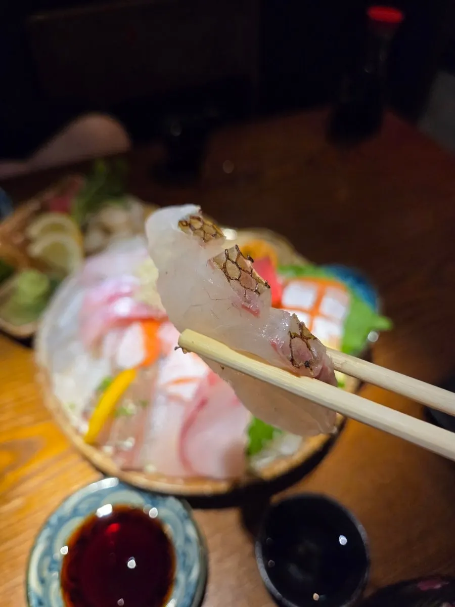 A glass of sake next to the sashimi plate