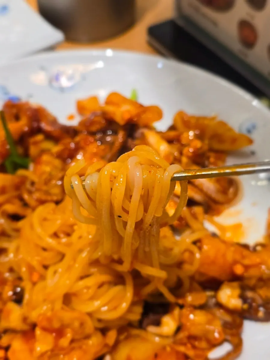 Lifting up a forkful of chewy jjolmyeon noodles