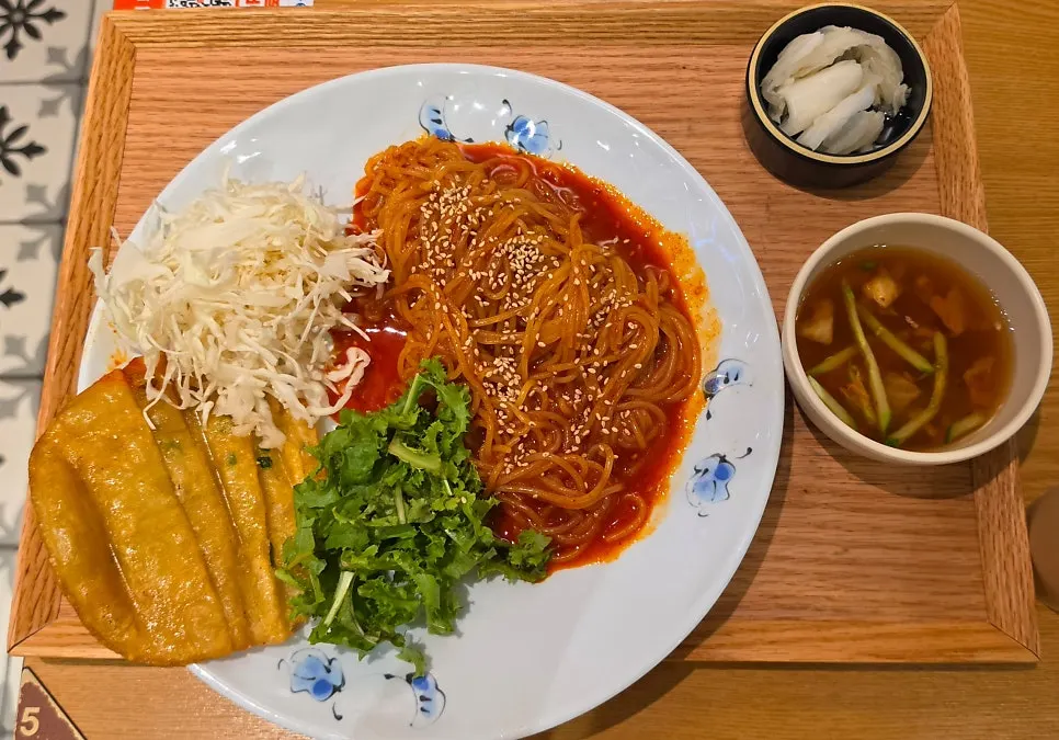 비빔쫄면과 납작만두, 채소가 담긴 큰 접시