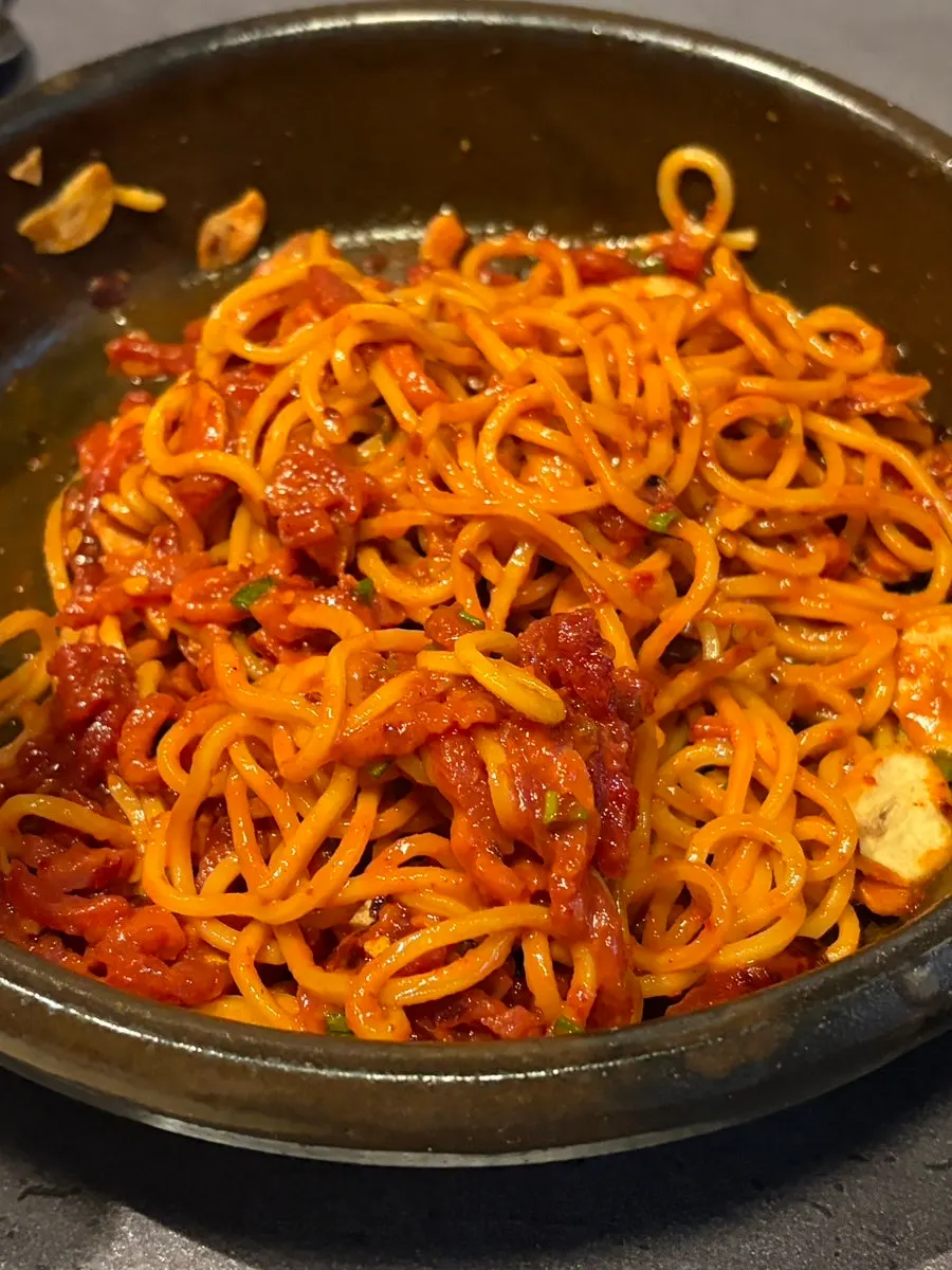 A spicy sauce-coated bite of tartare bibim noodles