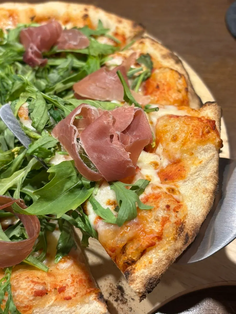 Close-up of the pizza loaded with arugula and jambon