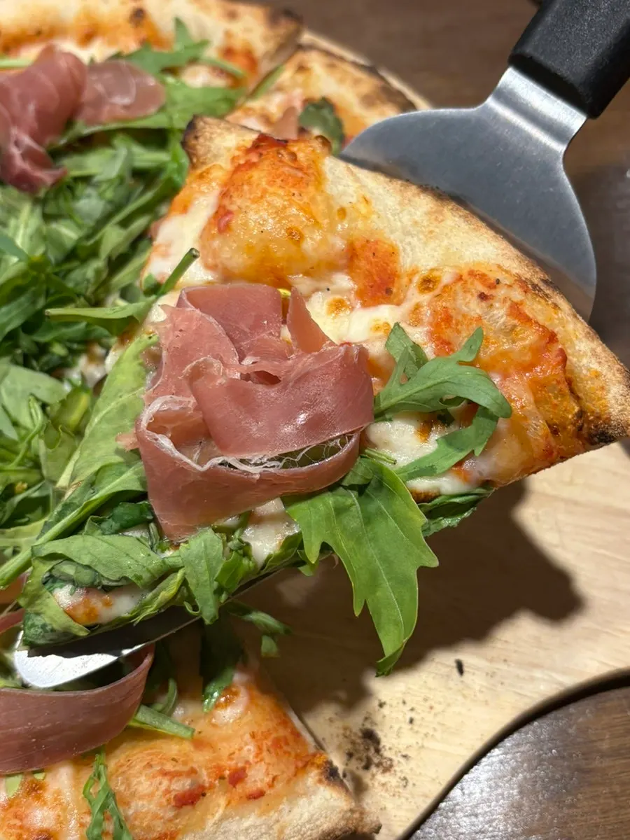Lifting a slice of wood-fired pizza