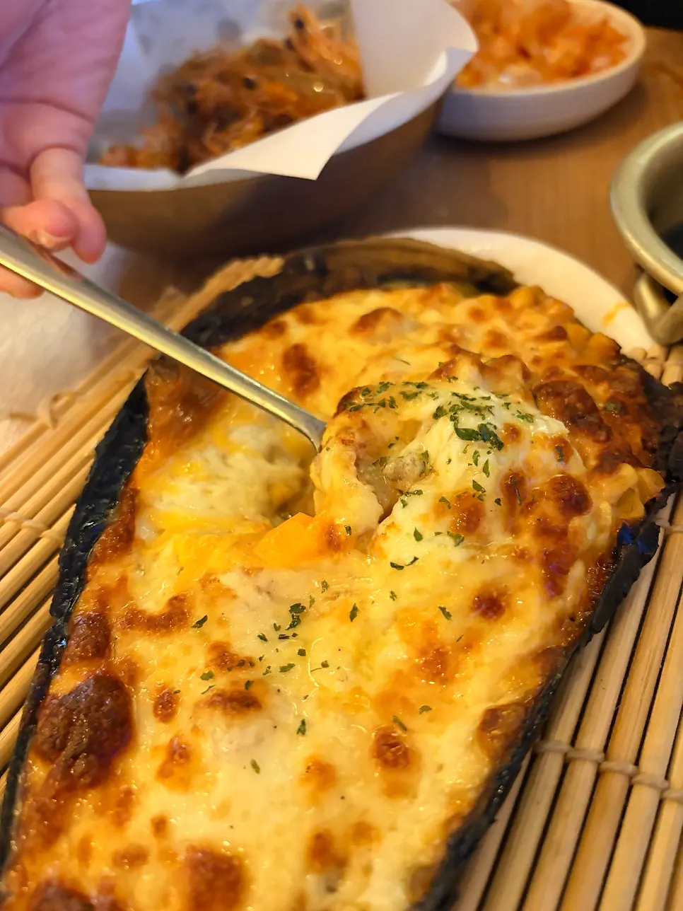 Cheese stretching as it's scooped from the scallop bake